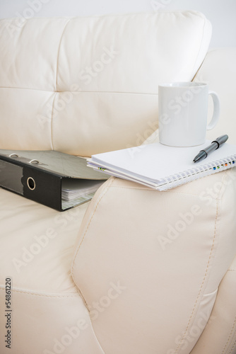 coffee cup, pen, notebook  ,document file is on white sofa