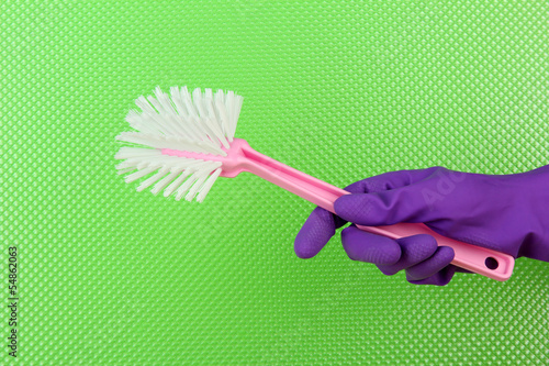 Toilet brush in hand on green background