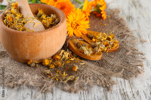 Fototapeta Naklejka Na Ścianę i Meble -  Fresh and dried calendula flowers in mortar on wooden