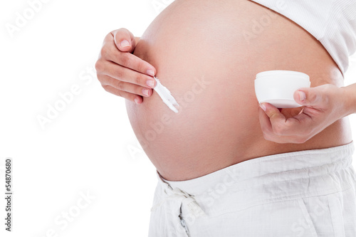 Pregnant woman putting cream on her  belly photo