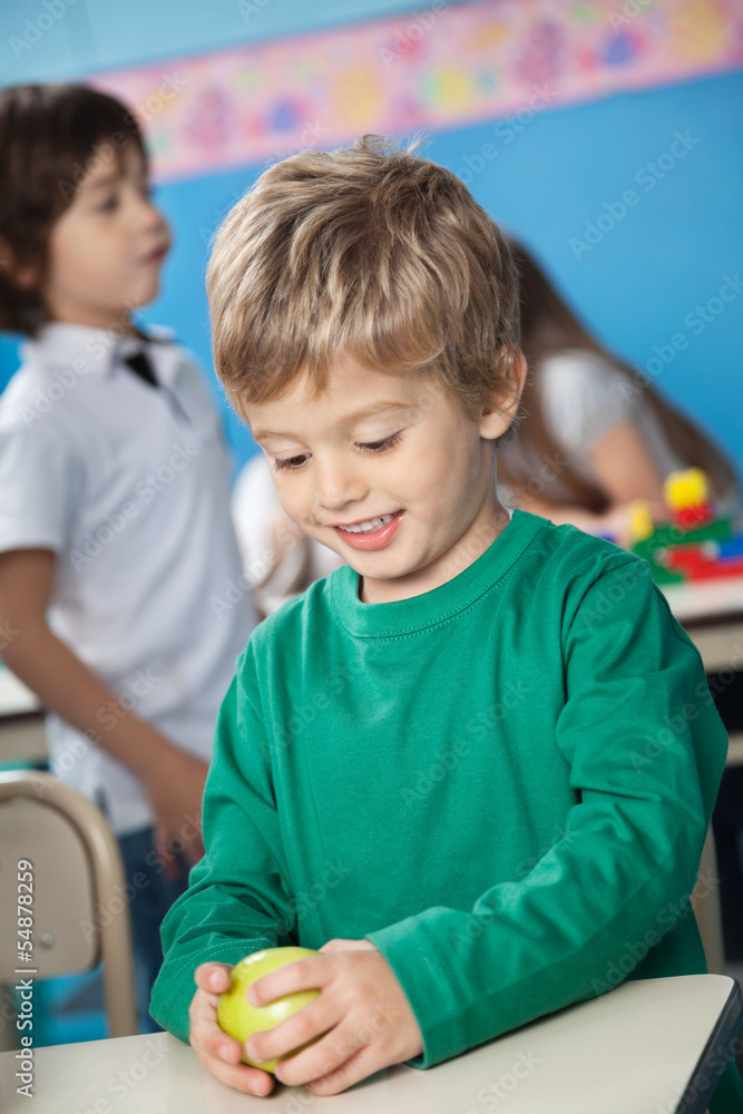 Obraz premium Boy Holding Smith Apple With Classmate In Background
