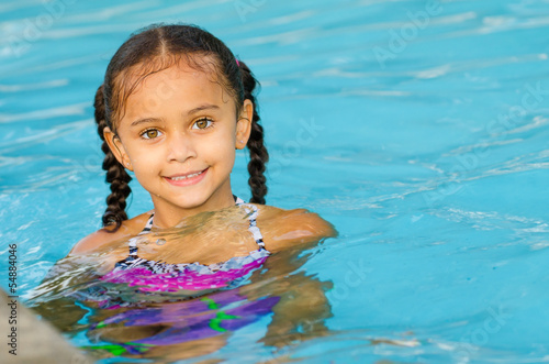Portrait of happy pretty mixed race child by side of pool 