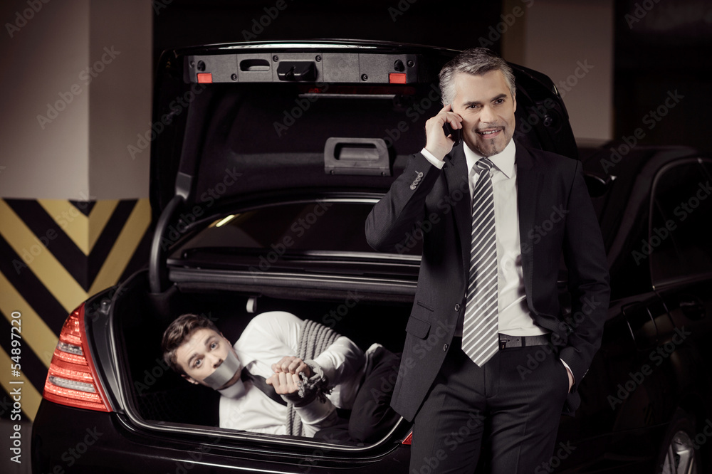Kidnapped man. Tied up businessman lying in the car trunk and lo Stock
