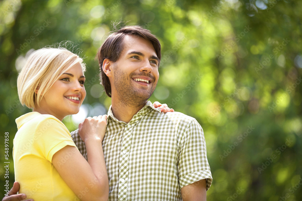 Loving couple in park. Happy young couple standing close to each Loving couple in park. Happy young couple standing close to each