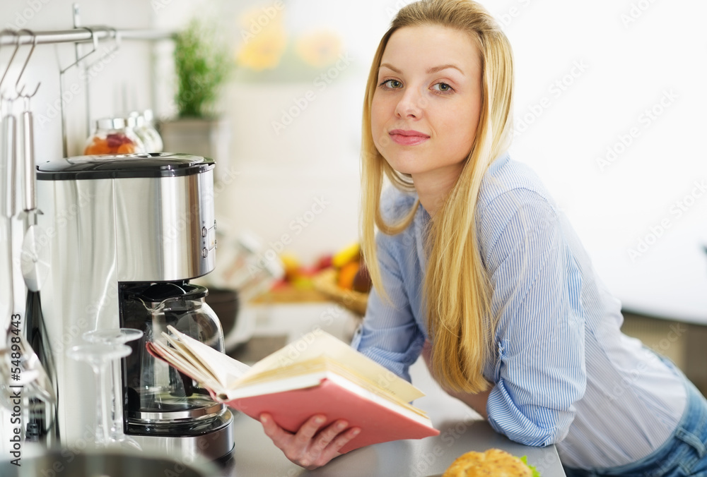 Teenager girl reading book in kitchen Teenager girl reading book in kitchen