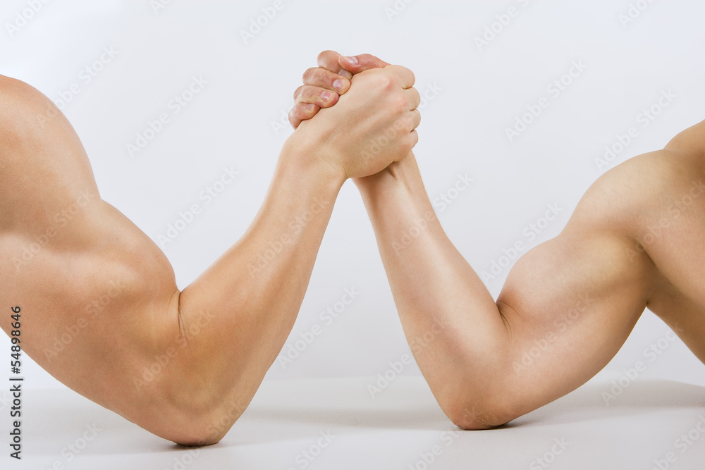 Two muscular hands clasped arm wrestling Two muscular hands clasped arm wrestling