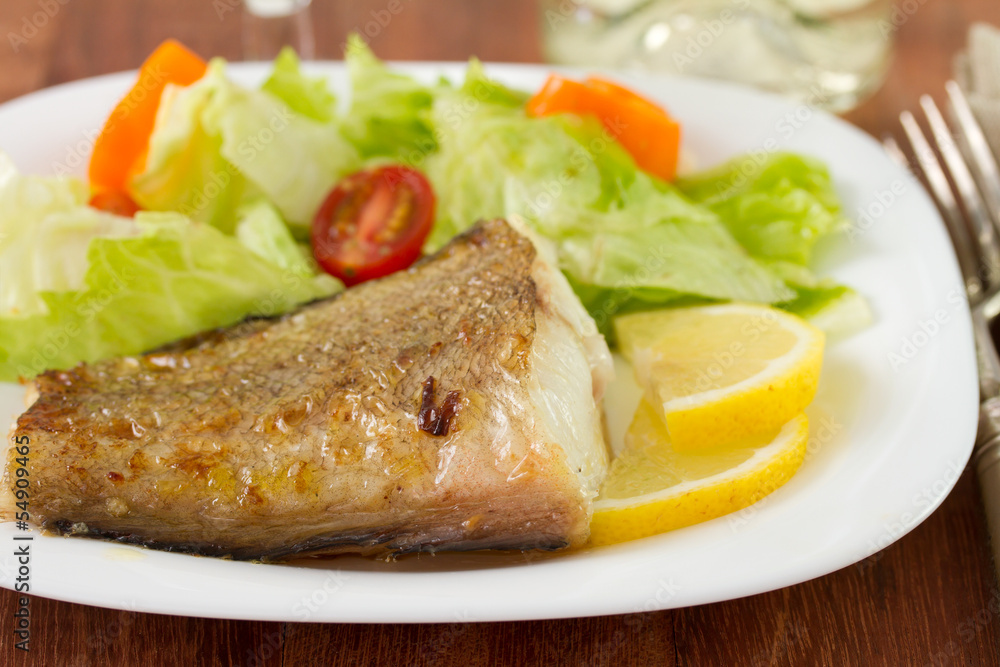 fried fish with salad and lemon on the plate