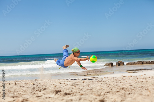 erwachsener junger sportlicher mann spielt beachvolleyball