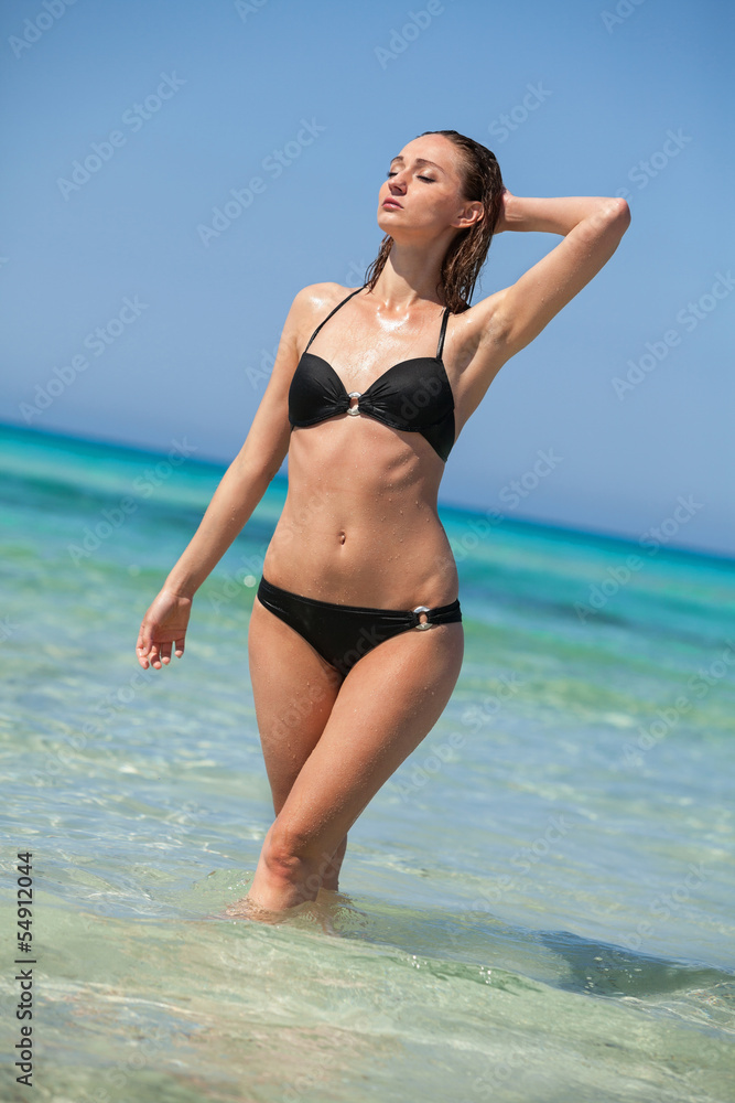 attraktive junge frau mit schwarzem bikini am strand