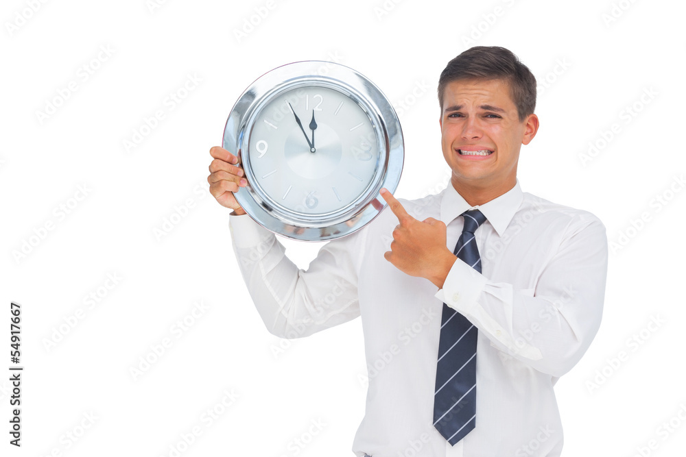 Anxious businessman holding and showing a clock Anxious businessman holding and showing a clock