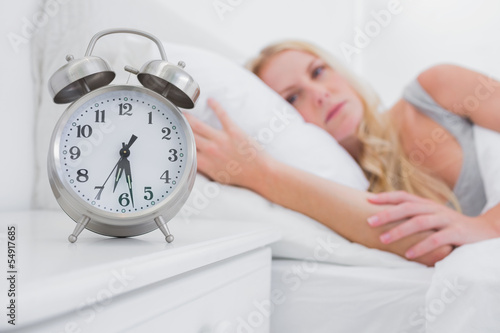 Tired woman looking at the alarm clock