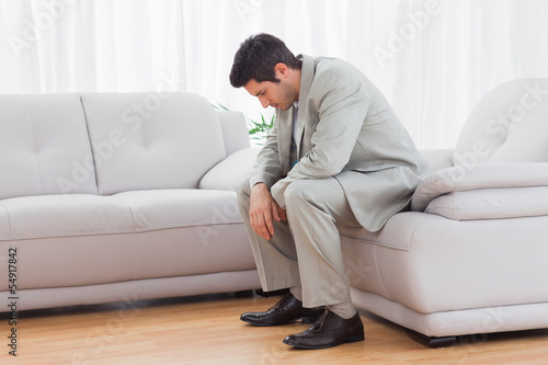 Unhappy buinessman sitting on sofa lowering his head © WavebreakmediaMicro