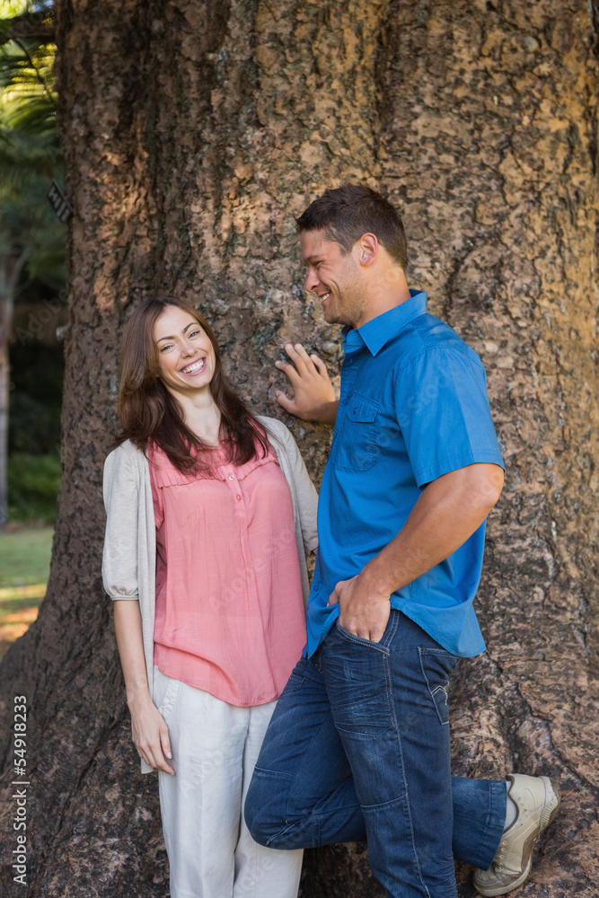 Smiling couple leaning on a tree Smiling couple leaning on a tree
