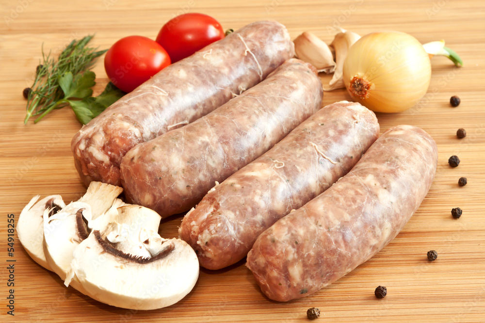 Uncooked sausages with vegetables on the chopping board Uncooked sausages with vegetables on the chopping board