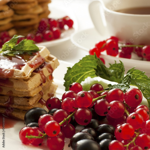 Freshly baked waffles with berries and tea cup