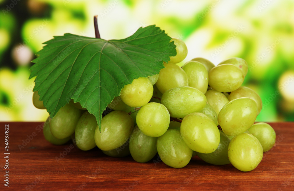 Ripe delicious grapes on table on bright background Ripe delicious grapes on table on bright background