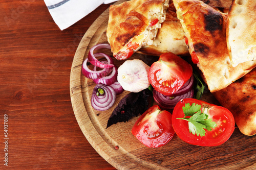 Pizza calzones on wooden board near napkin on wooden table
