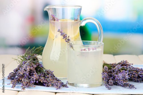 Lavender lemonade in glass jug, on napkin, on bright background