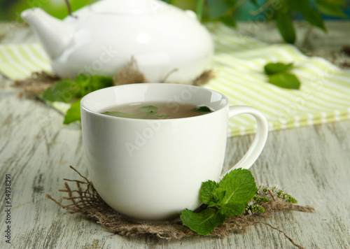 Cup of herbal tea with fresh mint on wooden table