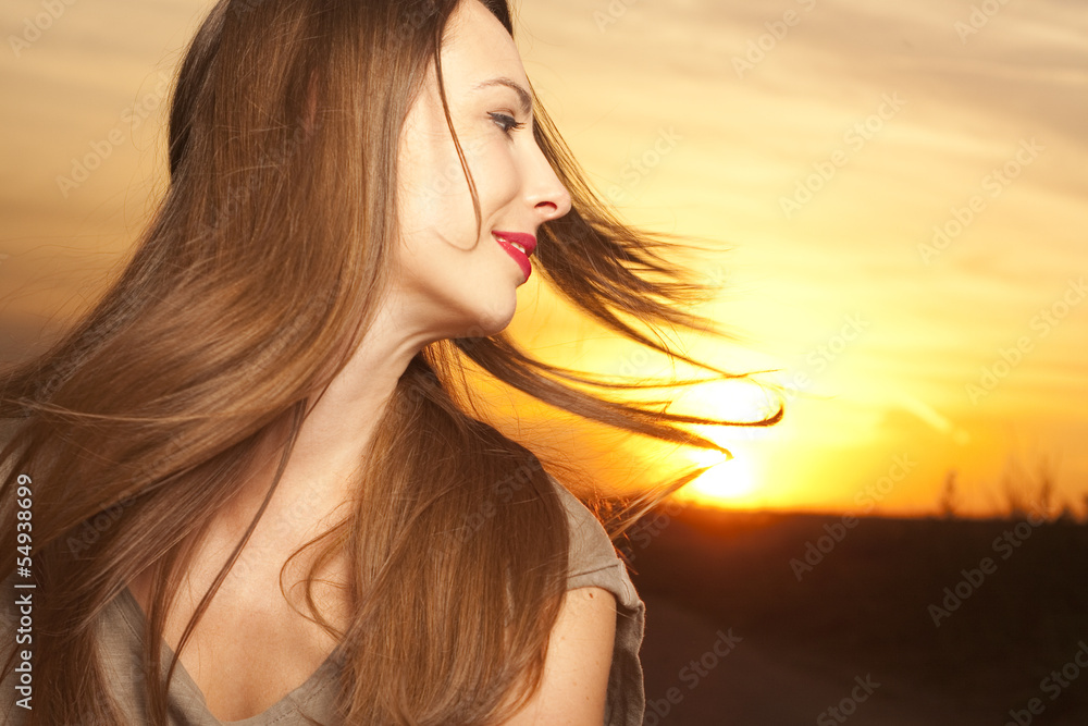 Fototapeta premium Beautiful and happy woman in front of sunrise background