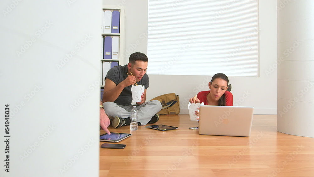 Hispanic and Caucasian office workers eating food on floor Hispanic and Caucasian office workers eating food on floor