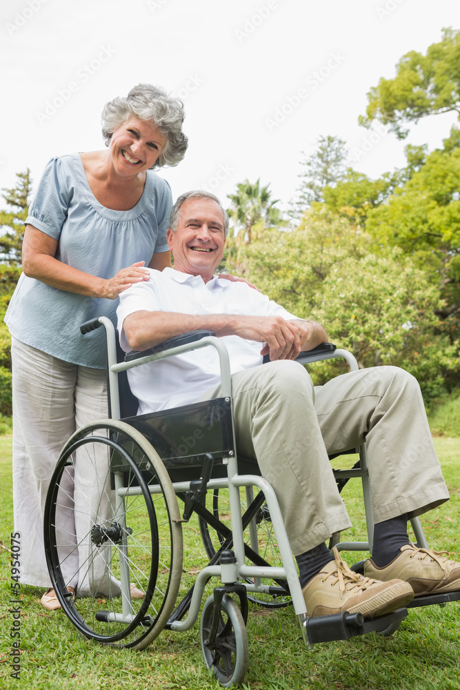Cheeful mature man in wheelchair with partner Cheeful mature man in wheelchair with partner