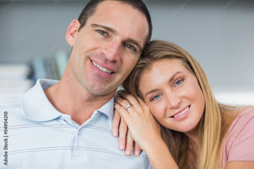 Attractive couple sitting on the couch smiling at camera Attractive couple sitting on the couch smiling at camera