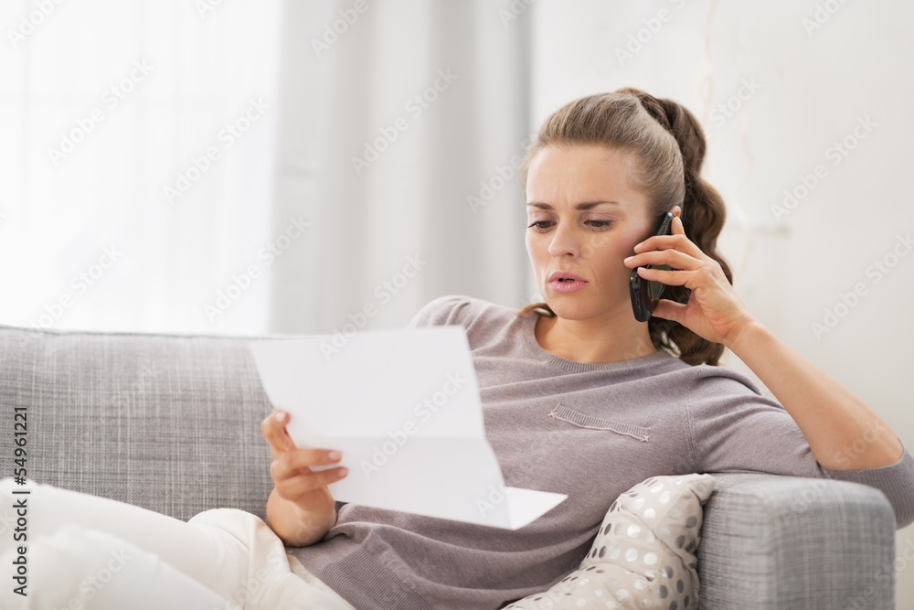 Concerned young woman with letter and talking cell phone Concerned young woman with letter and talking cell phone