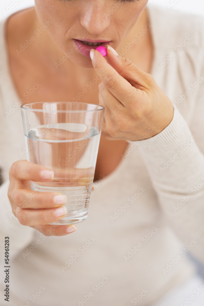 Closeup on young woman eating pill