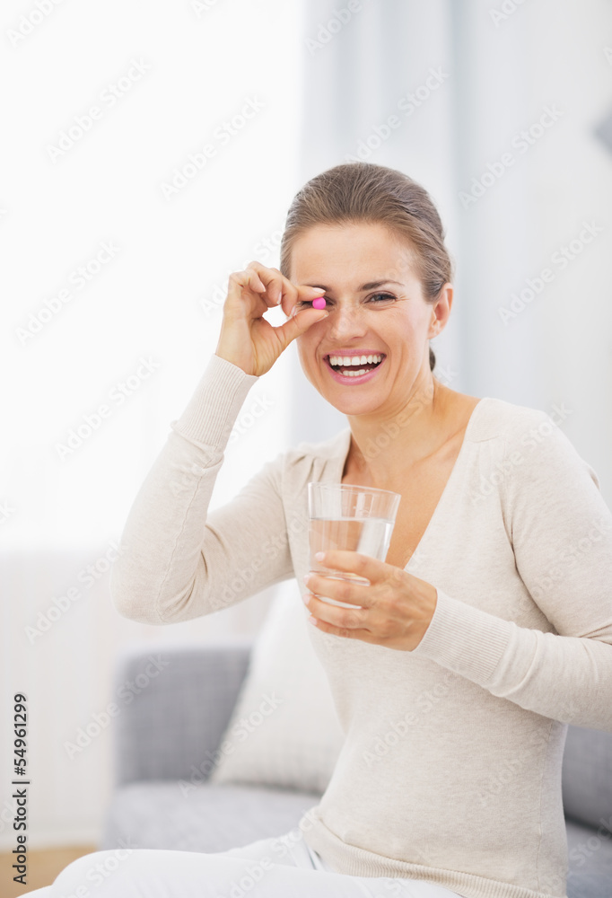 Happy young woman holding pill and glass of water Happy young woman holding pill and glass of water