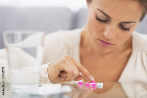 Closeup on frustrated young woman playing with pills