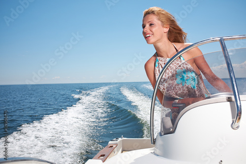 Photo Summer vacation - young girl driving a motor boat