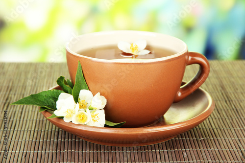 Cup of tea with jasmine  on bamboo mat  on bright background