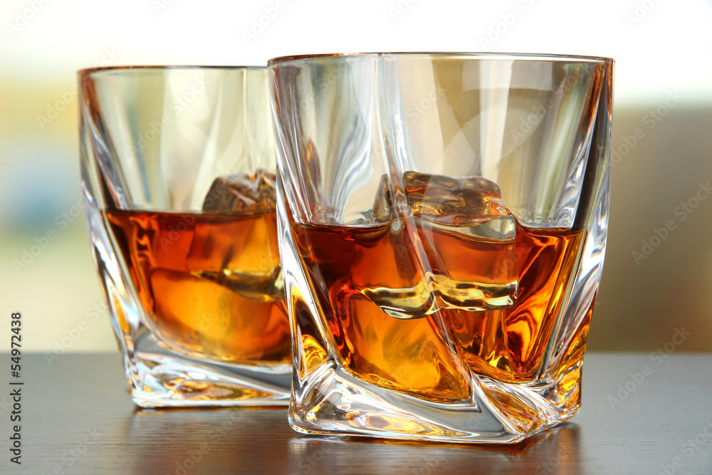 Glasses of whiskey, on bright background