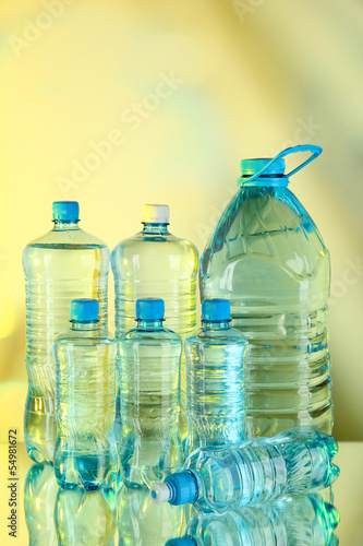 Water in different bottles on light background