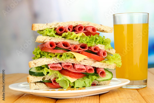 Huge sandwich on wooden table  on bright background