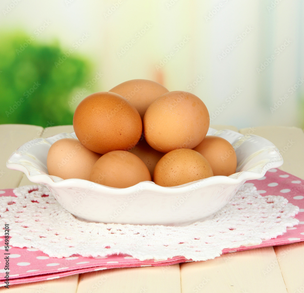 Eggs in plate on wooden table on natural background