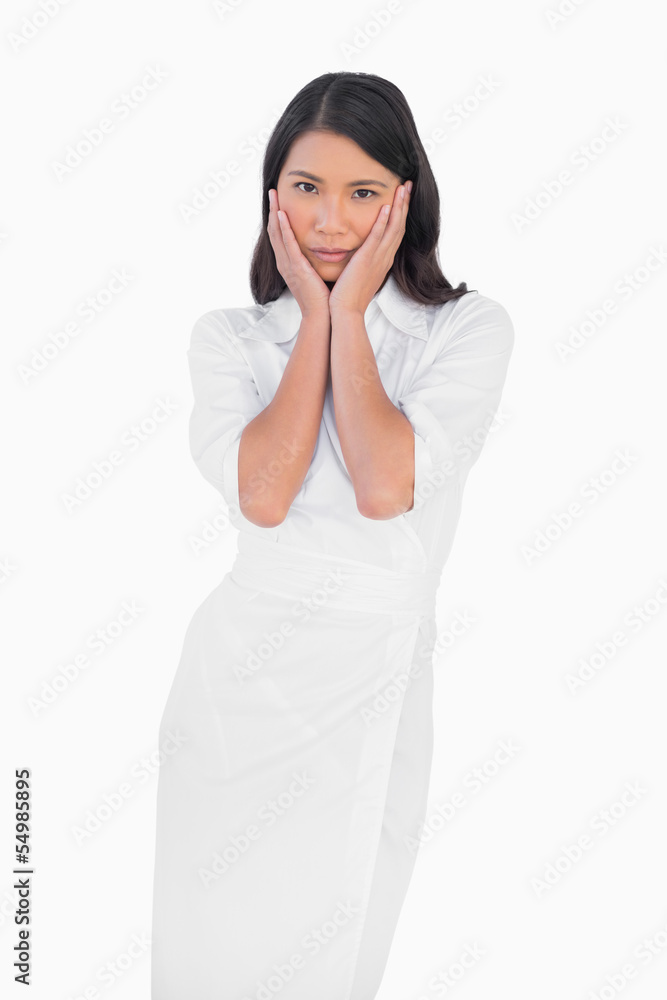 Elegant dark haired model wearing white dress touching her face Elegant dark haired model wearing white dress touching her face