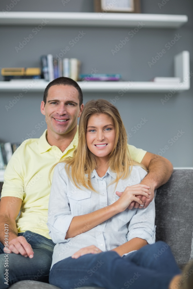 Smiling couple sitting on their couch Smiling couple sitting on their couch