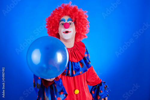 Happy clown with balloon on blue background