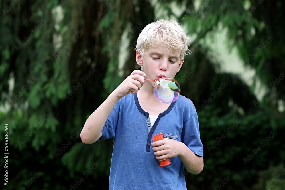 Cute boy blowing big soap bubble Cute boy blowing big soap bubble