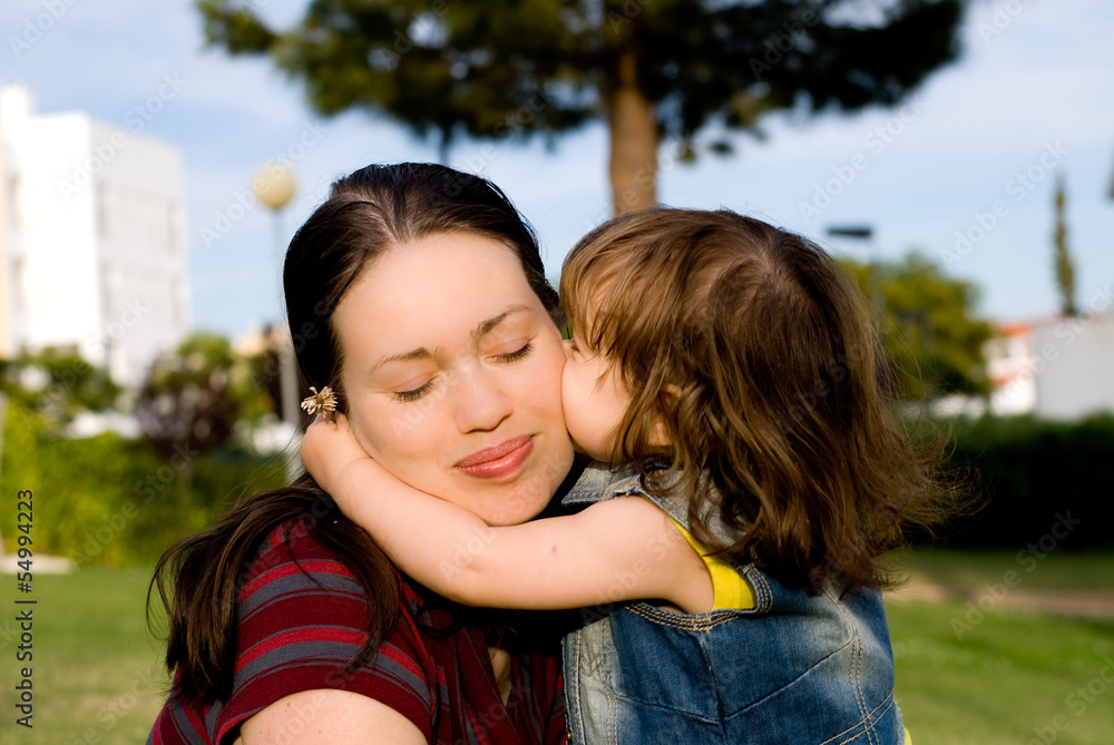 The little girl is kissing her mother The little girl is kissing her mother