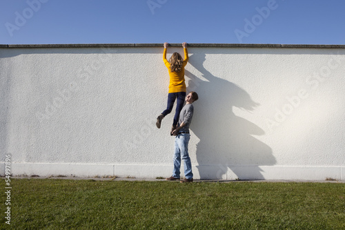 Germany, Bavaria, Munich, Young couple climbing wall photo