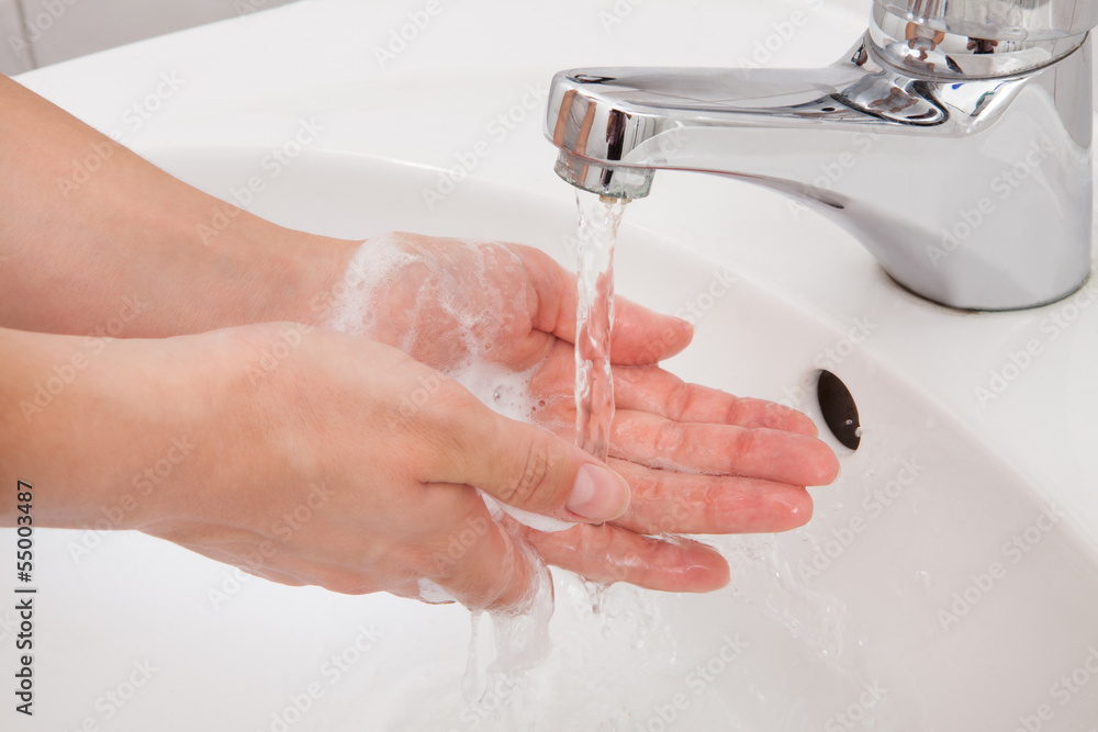 Human hands being washed under faucet Human hands being washed under faucet