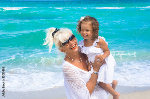 Foto Grandmother and granddaughter are having fun on the beach