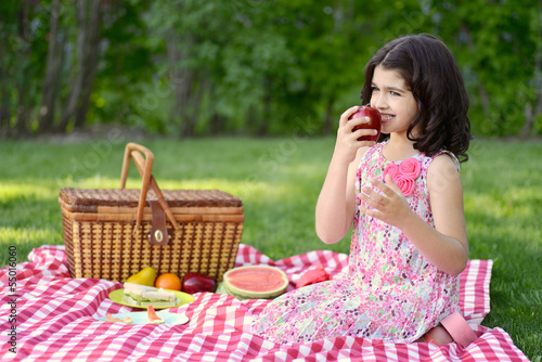 little girl eating apple at picnic