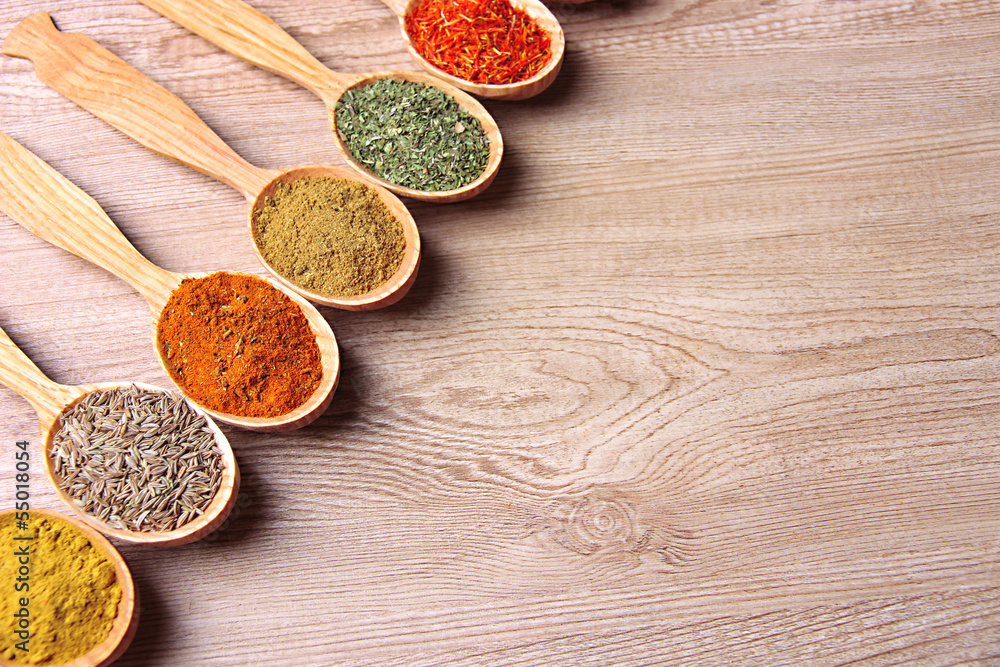 Fototapeta premium Assortment of spices in wooden spoons on wooden background