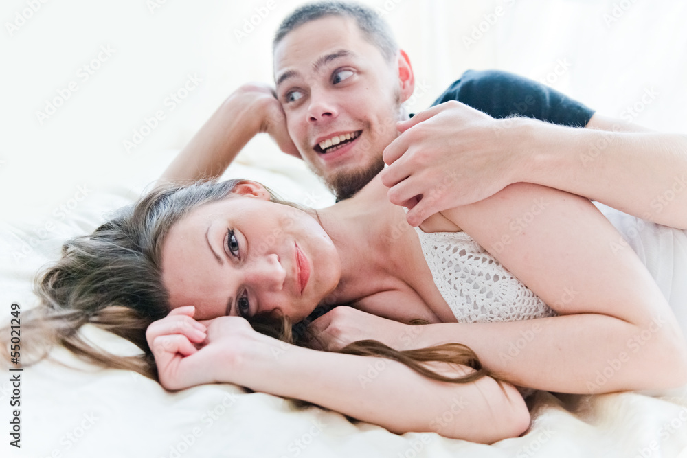 Lovely couple hugging on their bed at home Lovely couple hugging on their bed at home