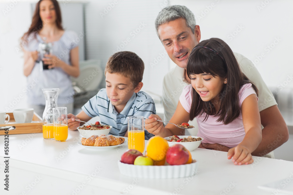 Cute family eating breakfast in kitchen together