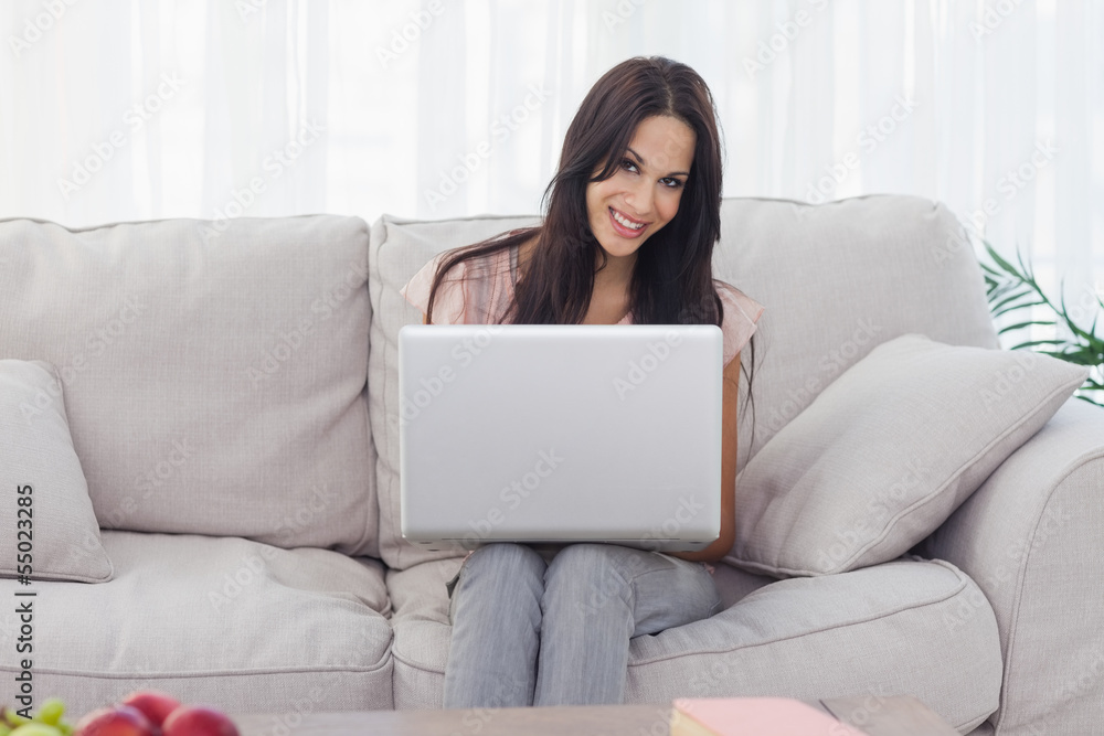 Attractive brunette using her laptop smiling at camera Attractive brunette using her laptop smiling at camera
